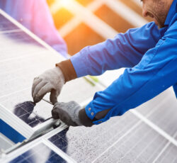 Smiling,male,technician,in,blue,suit,installing,photovoltaic,blue,solar